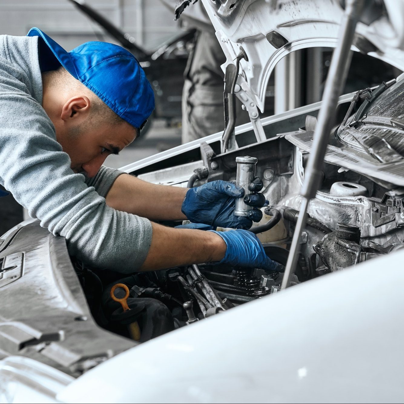 Mechanic in blue overalls checking serviceability of car engine